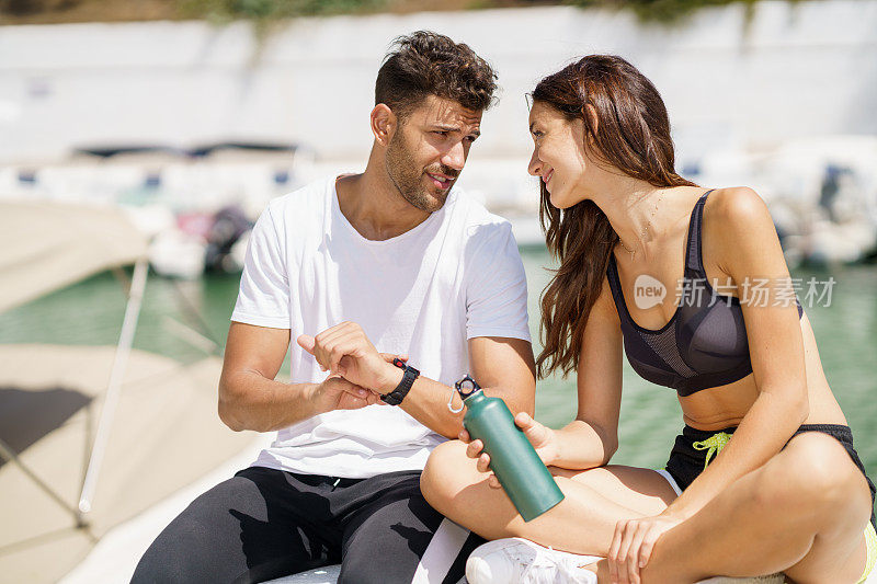 男子在运动后在一块运动表上向女子展示他的标记。人用smartwatch。