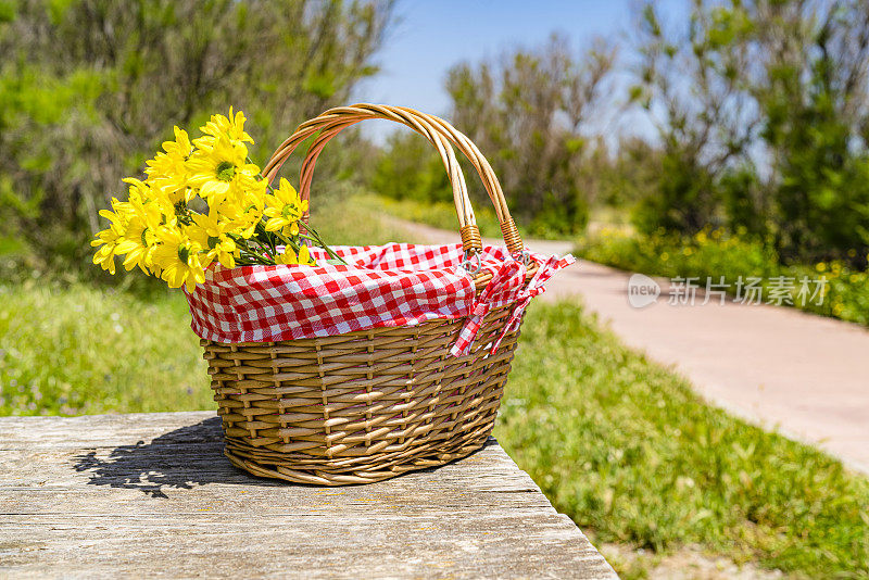 野餐柳条篮子与花在木制桌子在户外