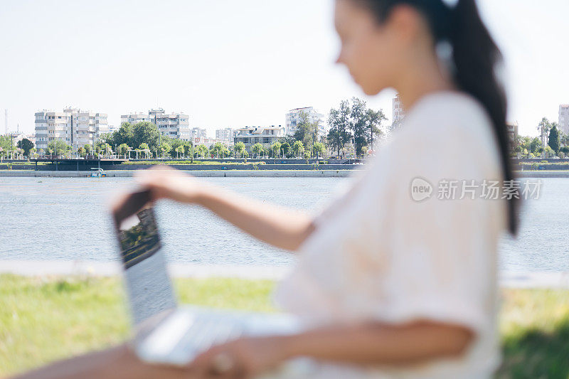 年轻女子在一个美丽的地方用笔记本电脑工作在大自然