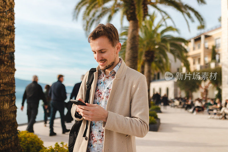 年轻的男性游客在一个陌生的城市度假时用手机当地图
