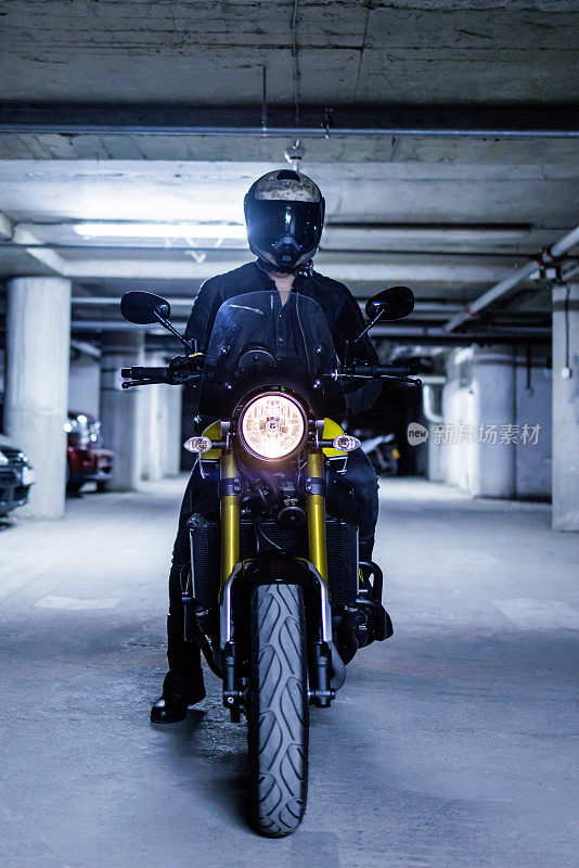 晚上在车库里骑着老式摩托车的摩托车手