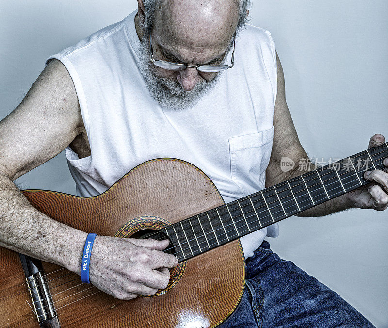 老年男性癌症幸存者演奏老式原声吉他