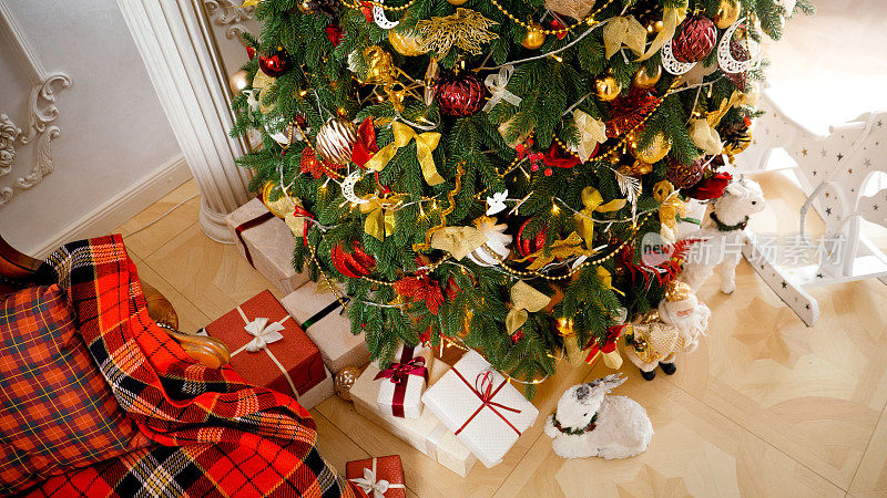 客厅里美丽的圣诞树的俯视图，上面装饰着轻花环和金色的小玩意。寒假背景或背景。