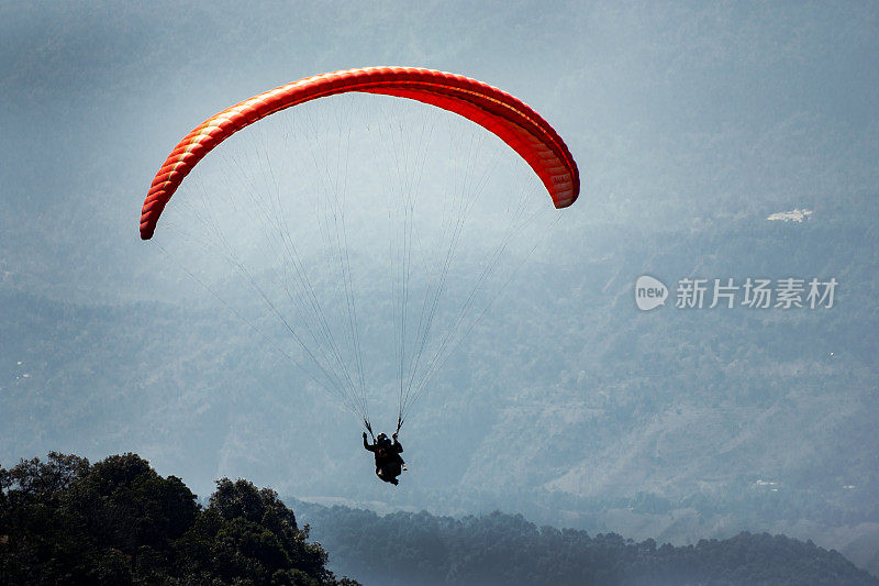 滑翔伞飞过城镇和山脉。