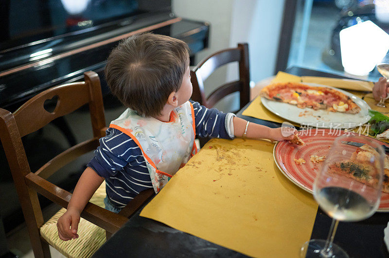 孩子在餐厅吃披萨在一个晚上的晚餐