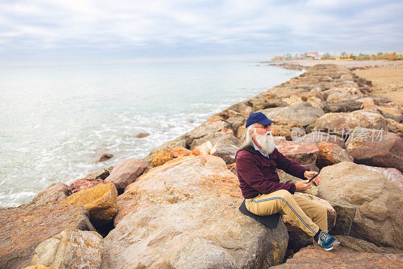 年长的成年男性在海边玩手机