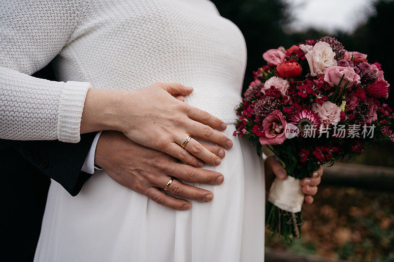 新婚夫妇与怀孕的新娘手捧鲜花和孕肚