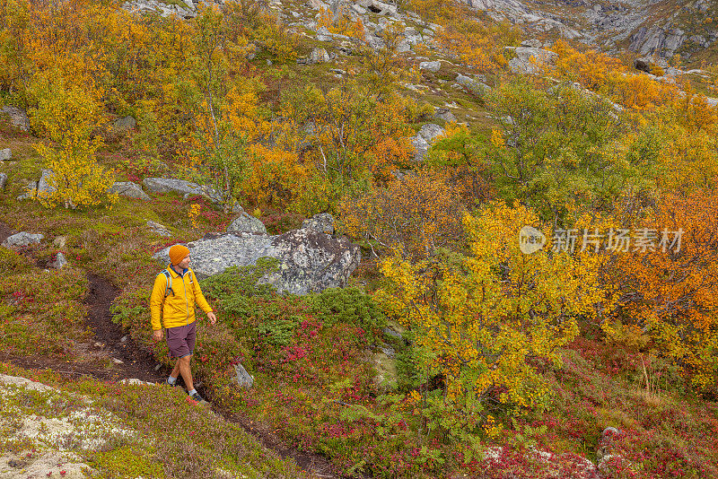 一个人在秋天的山里徒步旅行，他沿着小路走