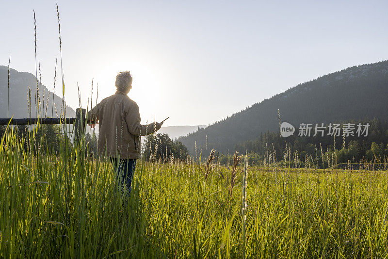 牧场主在木栅栏旁休息时使用数字平板电脑