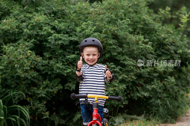 一个快乐的小男孩戴着头盔在户外骑着跑步自行车。一个快乐的孩子正在从事一项积极的运动。保护。人寿保险和儿童安全。