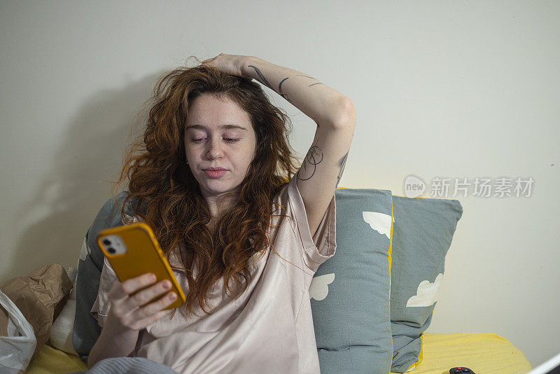 在床上用智能手机玩社交网络。女孩在卧室里休息，睡觉前查看信息。