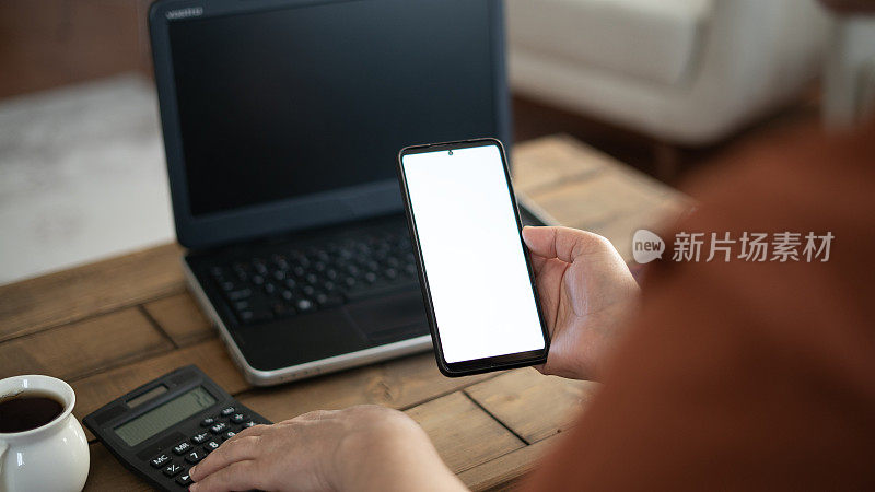 特写:女人在家里使用笔记本电脑和手机，屏幕模型