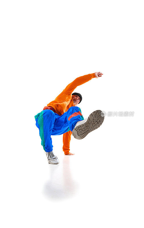 年轻灵活的体育男子跳霹雳舞，鲜艳的橙色和蓝色运动制服装备在白色的工作室背景。