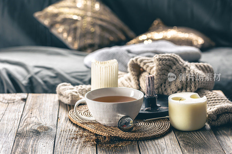 温馨的家居构图，一杯茶，蜡烛和针织元素。