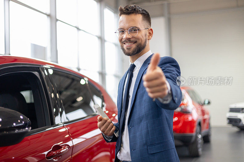 在汽车经销店，一名男子在红色汽车前竖起大拇指