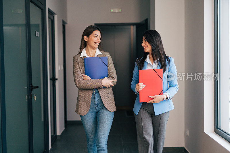 两个年轻的女商人在商业走廊里聊天