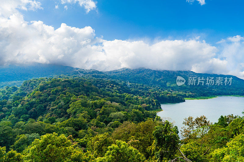 贝拉坦湖被郁郁葱葱的绿色森林环绕，背景是山脉。