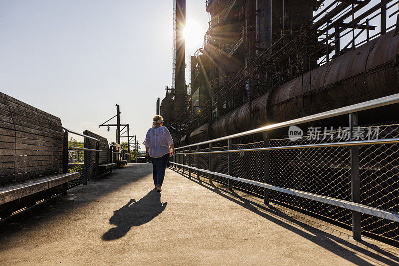 日落时分，一名妇女在参观宾夕法尼亚州伯利恒的老钢铁厂。过去最大的蒸馏厂之一现在是旅游地标