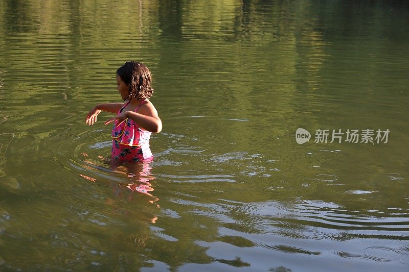 女孩走进淡水湖，在一根圆木上保持平衡