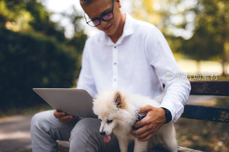 一个年轻人和他的博美犬在公园里