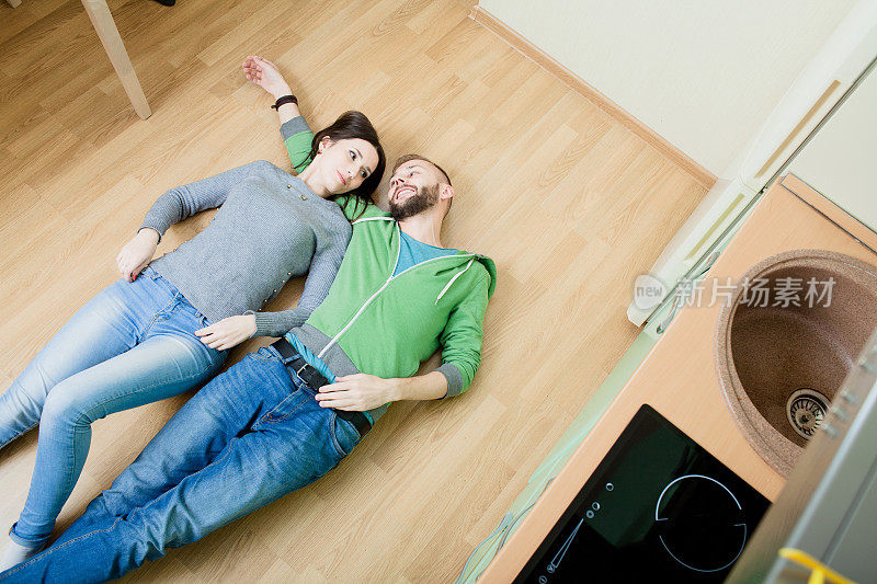 一对夫妇躺在厨房的地板上拥抱着