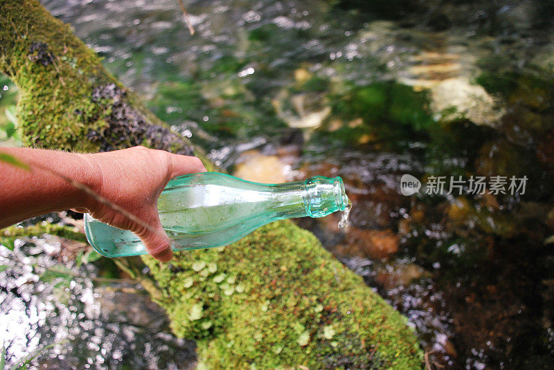 淡水水概念;玻璃水瓶与河流背景