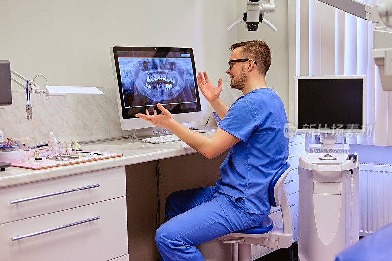 牙医在牙科诊所的电脑上看牙齿的x光。
