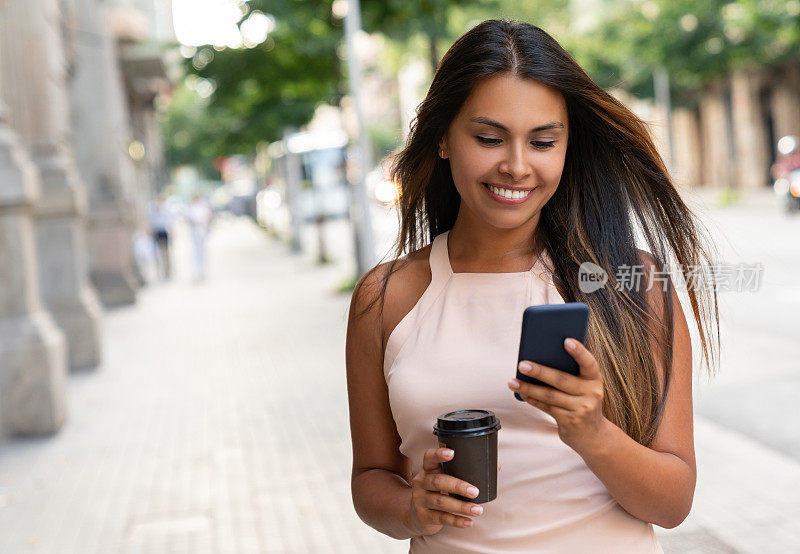 在街上用手机喝咖啡的女人