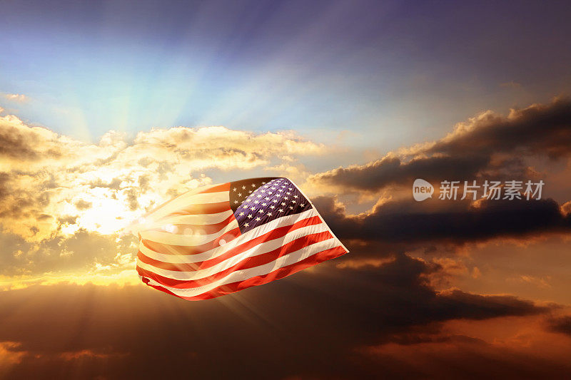 在多云的日落天空飘扬着美国国旗
