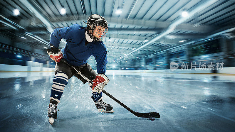 年轻的曲棍球运动员准备在冰上竞技场的背景下做一个强有力的射击