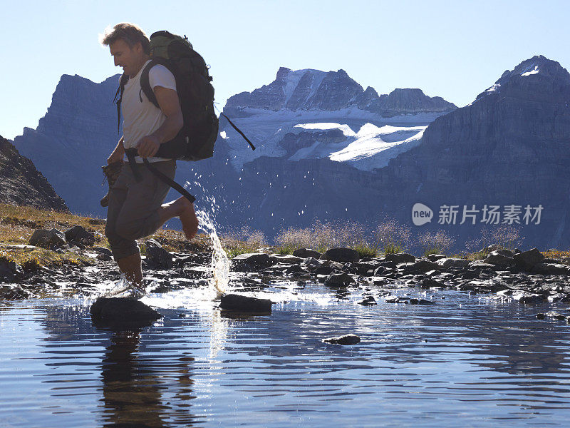 一名男性徒步旅行者在山间的小溪中溅起水花