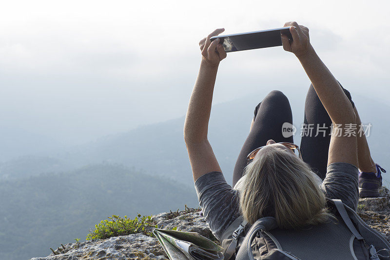 女性徒步者在山顶使用平板电脑