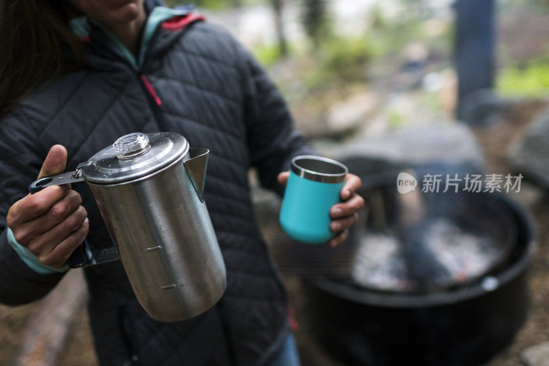 清晨，一名女性准备在营地喝她的第一杯新煮的咖啡