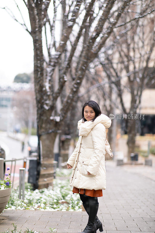 年轻女子站在城市街道上，东京正在下雪