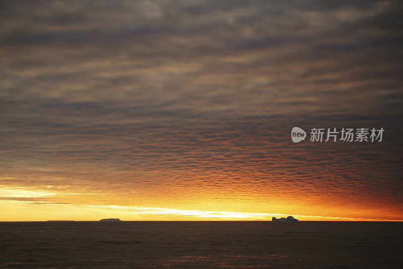 南极泻湖上的日落与漂流的冰山和雪峰的背景，勒梅尔海峡，南极洲