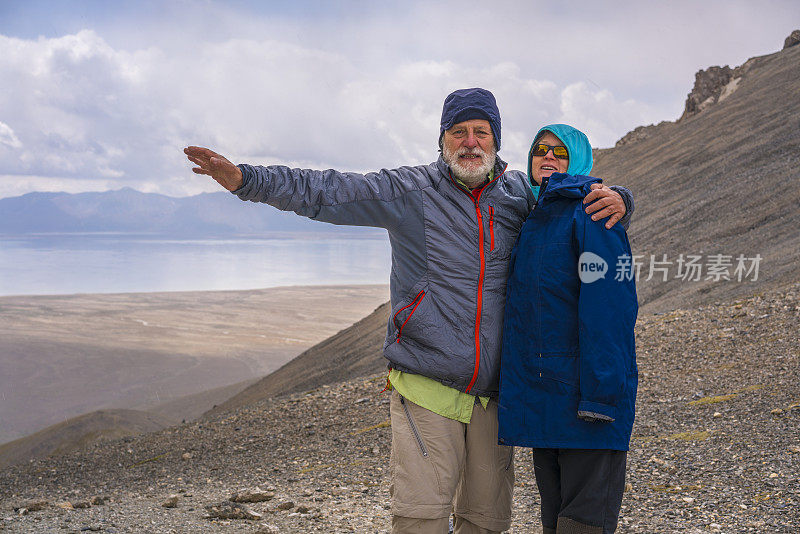 在中吉边境附近4000米高的山口上，徒步旅行者，年长的男女，举起一只手