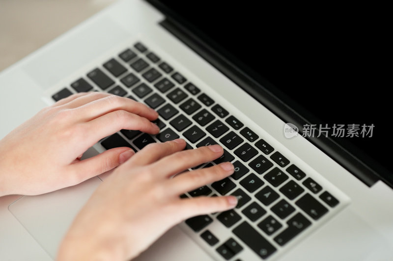 女性的手在笔记本电脑键盘上