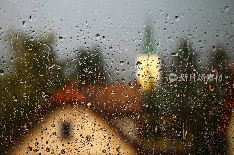 雨点落在窗户上，房子和教堂是背景