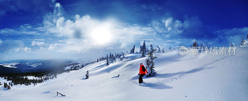 在夕阳的映衬下，滑雪者从高山上往山下滑雪