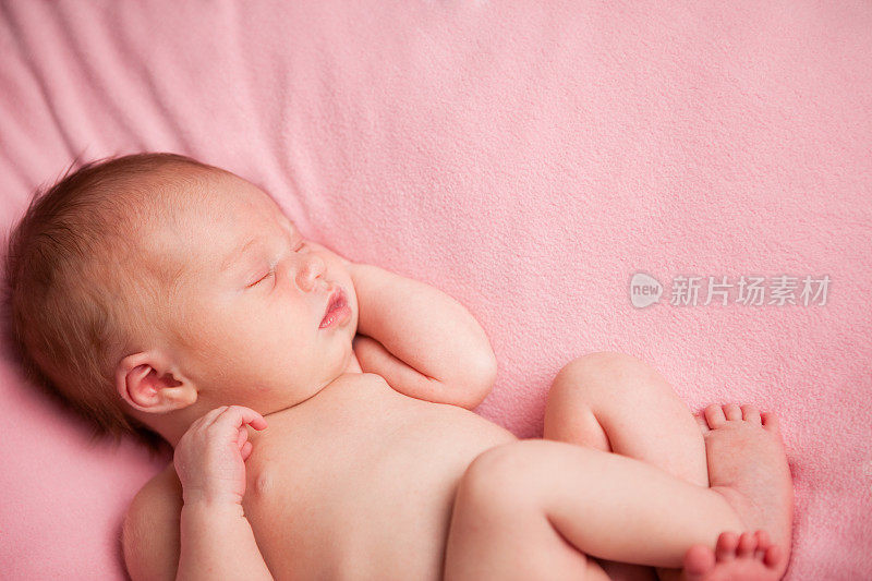 新生女婴安静地睡在粉红色的毯子上
