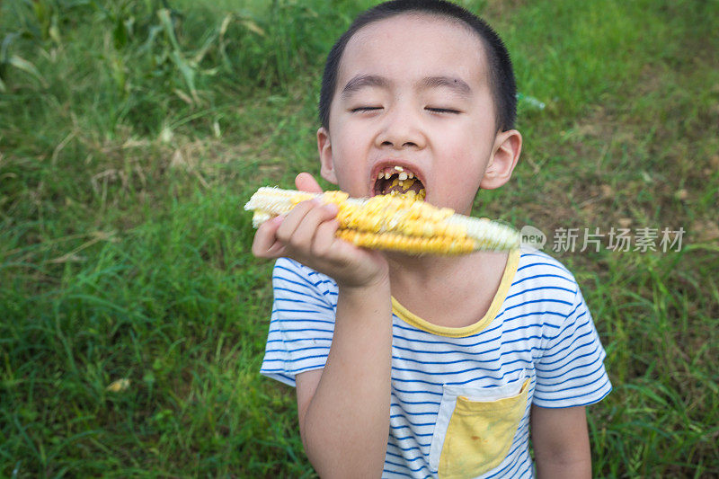 嘴里叼着生玉米的中国男孩