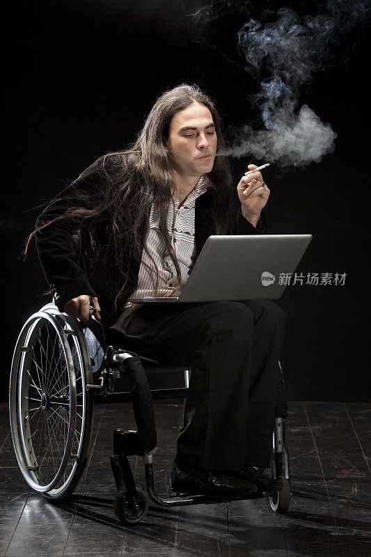 使用笔记本电脑吸烟的轮椅使用者。