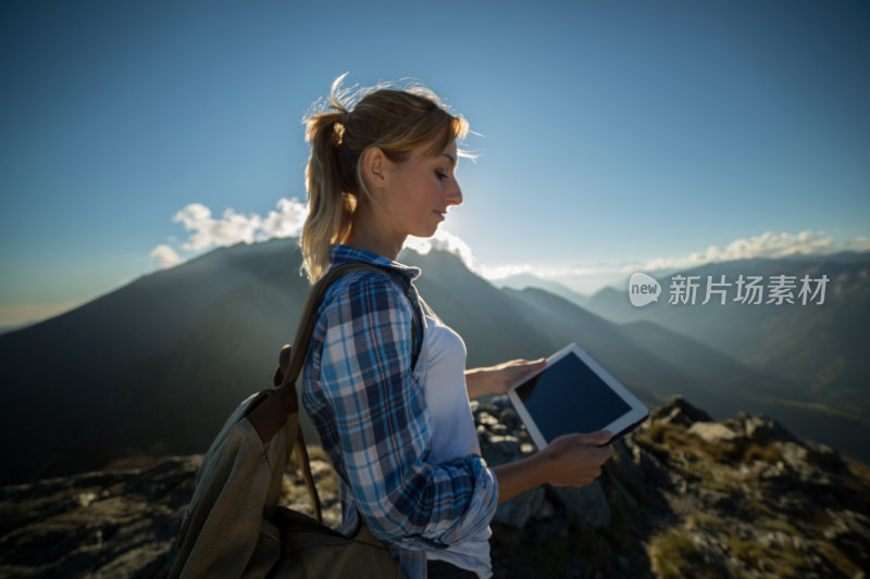 年轻女子在山顶用平板电脑