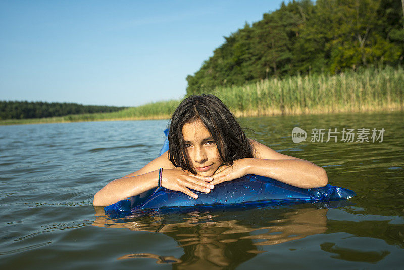 夏天的时候，沉思的年轻女孩放松在泳池筏