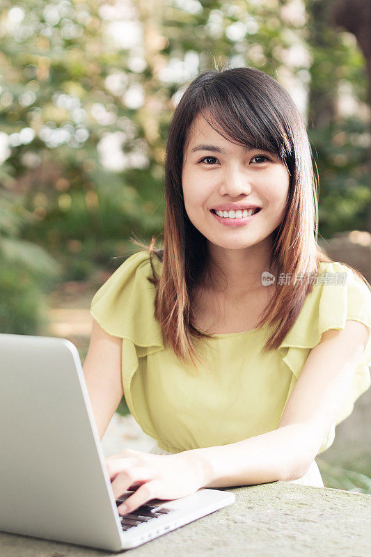 亚洲女学生在校园里用笔记本电脑的肖像