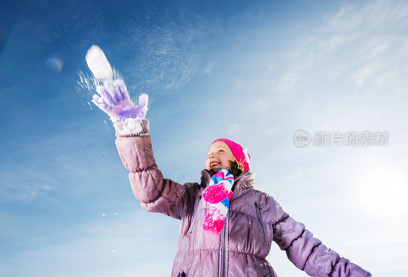 小女孩对着天空打雪仗。