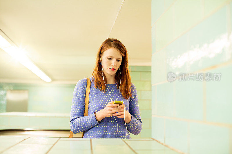 年轻女子在地铁站使用手机