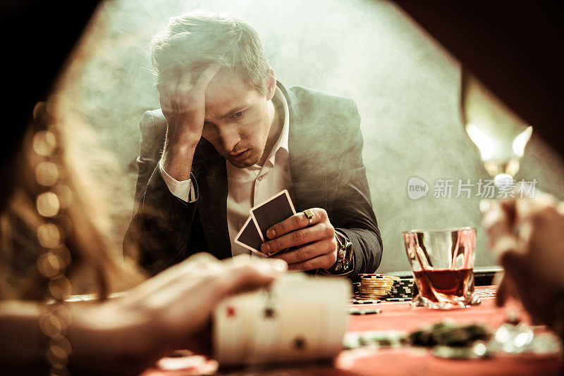 肖像沮丧的人看着手中的扑克牌