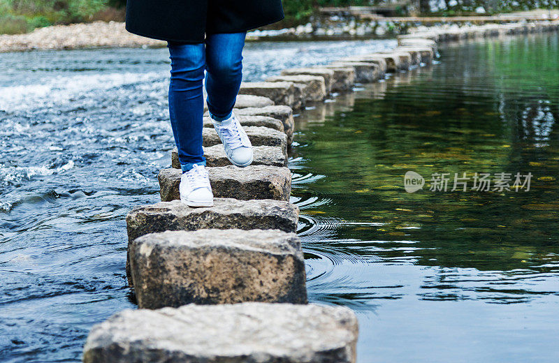 在河上踏着石头过河的女人