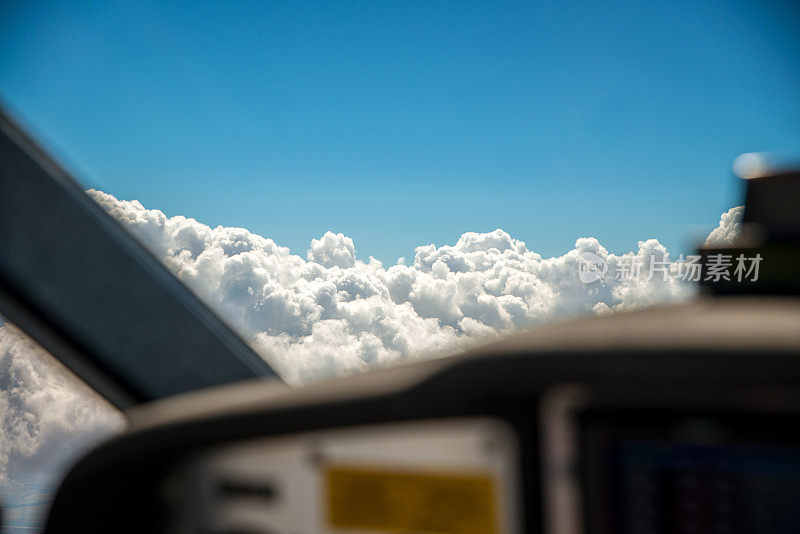 一架在7000英尺高空飞行的小型飞机的驾驶舱，选择性地聚焦于前窗外的高积云。